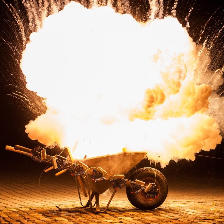 Eine brennende Schubkarre mit großem Feuerball und Funkenausstoß.